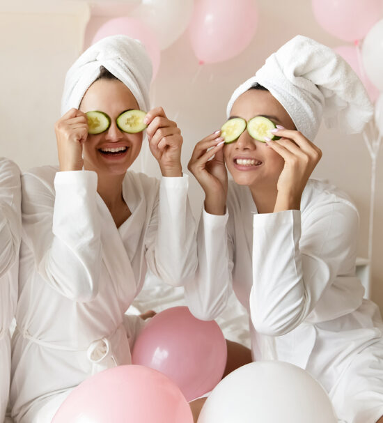 Overjoyed multiethnic millennial girls wearing bathrobes have fun make beauty procedures enjoy bachelorette bridal shower at spa or hotel, happy multiracial female friends celebrate hen party